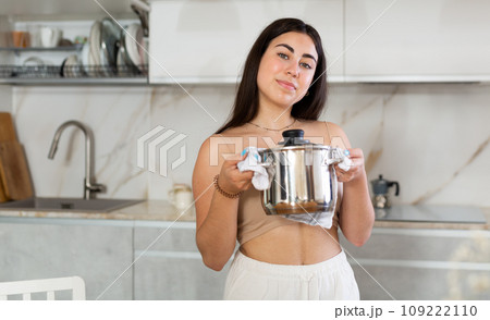 Young woman posing with saucepan in kitchen at home Young woman posing with saucepan in kitchen at home 109222110