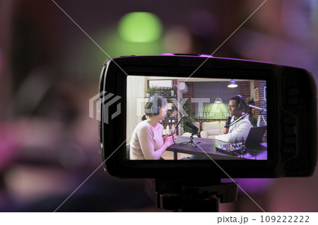 Close up shot focused on preview image on professional camera with podcast host and african american guest enjoying conversation in blurry background. Professional recording equipment in home studio Close up shot focused on preview image on professional camera with podcast host and african american guest enjoying conversation in blurry background. Professional recording equipment in home studio 109222222