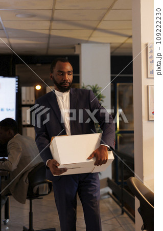 Stressed sad businessman getting fired from corporate job ready to leave office late at night. Upset executive manager packing personal belongings in cardboard box. Business concept Stressed sad businessman getting fired from corporate job ready to leave office late at night. Upset executive manager packing personal belongings in cardboard box. Business concept 109222230