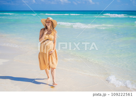 Radiant and expecting, a pregnant woman stands on a pristine snow-white tropical beach, celebrating the miracle of life against a backdrop of natural beauty Radiant and expecting, a pregnant woman stands on a pristine snow-white tropical beach, celebrating the miracle of life against a backdrop of natural beauty 109222561