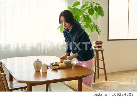 休日の朝、食事をテーブルに配膳する女性 109224903