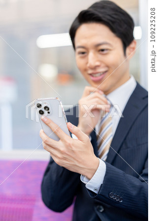 通勤電車でスマホを見るビジネスマン　撮影協力「京王電鉄株式会社」 109225208