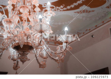 A stunning pink glass chandelier hangs in a neutral-toned room, creating a striking focal point. The elegant design adds a touch of glamour to any space. A stunning pink glass chandelier hangs in a neutral-toned room, creating a striking focal point. The elegant design adds a touch of glamour to any space. 109225973