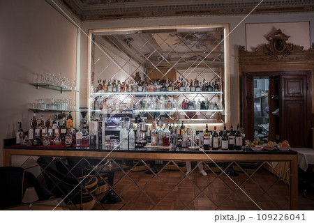 Dark and moody bar interior with a large mirror, bottles, and glasses on the counter. The atmosphere is mysterious and undefined. Perfect for a variety of concepts and designs. Dark and moody bar interior with a large mirror, bottles, and glasses on the counter. The atmosphere is mysterious and undefined. Perfect for a variety of concepts and designs. 109226041