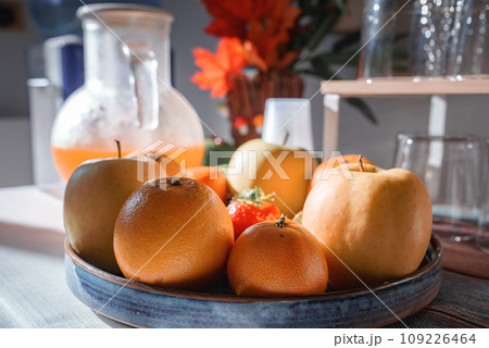 Close-up shot of vibrant oranges in a bowl and a pitcher on a table in a Venetian hotel or restaurant, evoking a relaxed and inviting summer atmosphere. 109226464