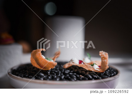 A close-up shot of a plate of black beans on a table. The type of cuisine and other food on the plate are unknown. 109226592