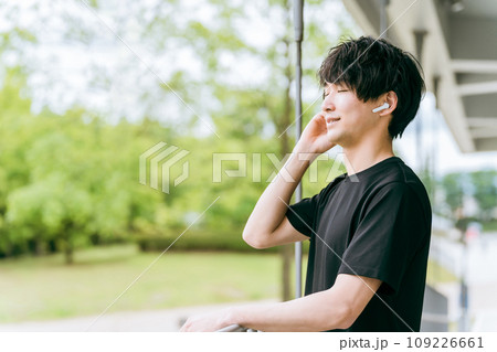 スポーツ・トレーニング中に高音質のワイヤレスイヤホンで音楽を聴く男性 109226661