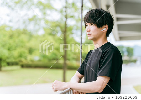 スポーツ・トレーニング中に高音質のワイヤレスイヤホンで音楽を聴く男性 109226669