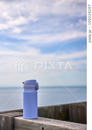 海を背景に木材の柱に置かれた水色の水筒 海を背景に木材の柱に置かれた水色の水筒 109228207