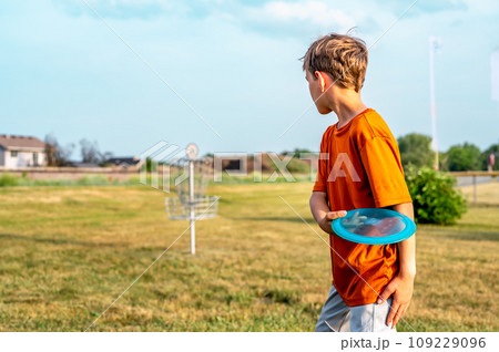 Young Caucasian male boy aiming a disc golf at a chain goal.  Young Caucasian male boy aiming a disc golf at a chain goal.  109229096