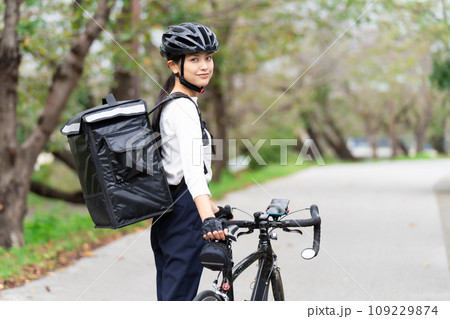 ロードバイクでフードデリバリー配達員をする若い女性 109229874