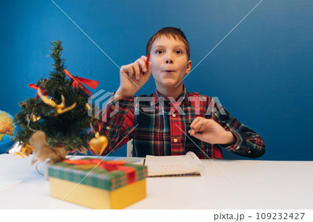 boy writing letter for Santa Claus for christmas sitting at the table at home 109232427