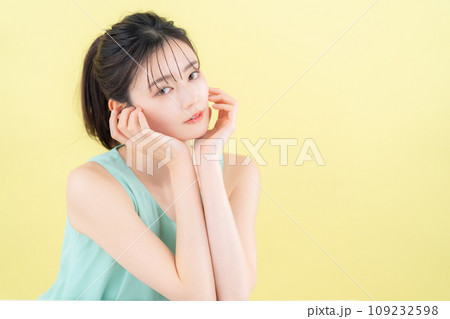イエローバックでスキンケアをする若い女性 イエローバックでスキンケアをする若い女性 109232598