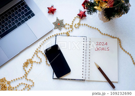 open notepad with Goals for new year text.lap top and christmas decorations 109232690