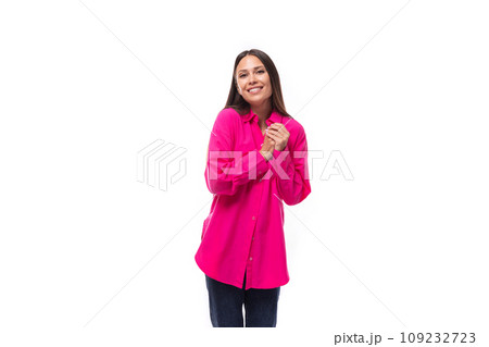 positive inspired young brunette lady dressed in a bright pink shirt and jeans on a white background 109232723