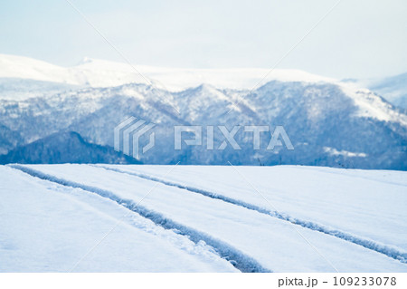 冬の北海道の道を走る車のタイヤ跡 109233078