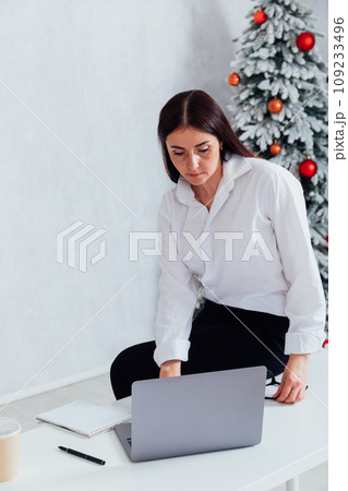 Business woman working online at computer at christmas tree Business woman working online at computer at christmas tree 109233496