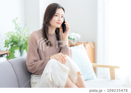 リビングのソファでスマホを使う若い女性 リビングのソファでスマホを使う若い女性 109235478