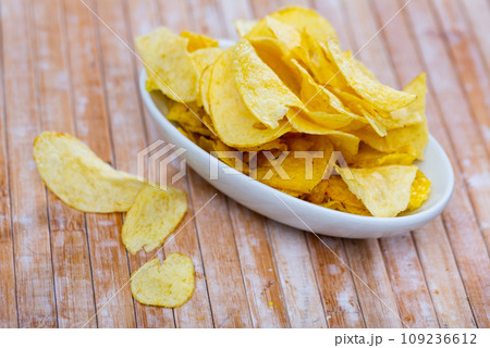 Pile of salty crunchy deep fried potato chips on plate Pile of salty crunchy deep fried potato chips on plate 109236612