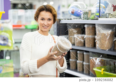 Young woman in animal goods store examines packaging of dry food for turtles Young woman in animal goods store examines packaging of dry food for turtles 109236882