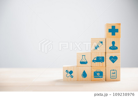 Representation of healthcare and insurance via pyramid-stacked wooden cubes. Crowning medical insurance icon suggests safety. Blue background presents copyspace for Health Insurance communication. Representation of healthcare and insurance via pyramid-stacked wooden cubes. Crowning medical insurance icon suggests safety. Blue background presents copyspace for Health Insurance communication. 109238976