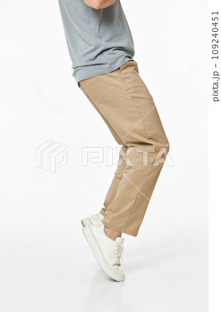 man wearing white sneakers and casual beige pants on studio background. side view 109240451
