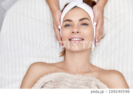 Beautiful woman getting face massage treatment in beauty salon. girl enjoys this procedure. Beautiful woman getting face massage treatment in beauty salon. girl enjoys this procedure. 109240596