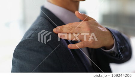 Businessman in business suit brushing off dust or dandruff from his shoulder closeup Businessman in business suit brushing off dust or dandruff from his shoulder closeup 109244206