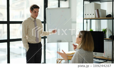 Business coach showing charts on blackboard to student in office Business coach showing charts on blackboard to student in office 109244287