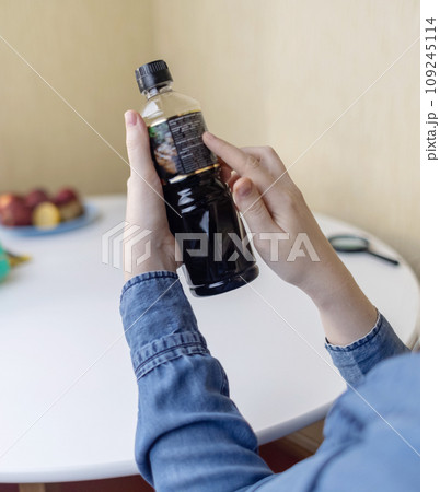 Woman reads instructions for food products at home. Checking labels on goods. Study of product compositions. Search Internet for descriptions of product gradients. Useful or harmful. Nutritionology 109245114