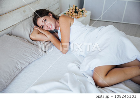 Beautiful blonde woman waking up in the morning in the bedroom on the bed Beautiful blonde woman waking up in the morning in the bedroom on the bed 109245303