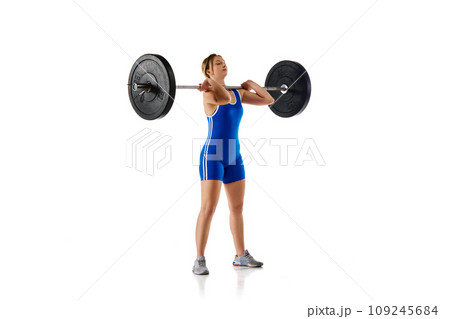Young girl with fit strong body, athlete training, lifting heavy weights, barbell against white background 109245684