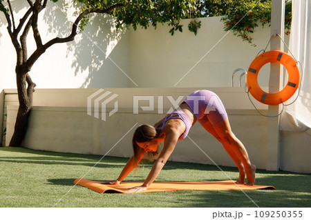 Flexible Woman Stretching on Yoga Mat Outdoors Flexible Woman Stretching on Yoga Mat Outdoors 109250355
