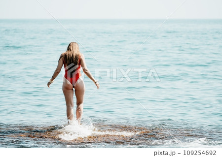 Woman sea yoga. Back view of free calm happy satisfied woman with long hair standing on top rock with yoga position against of sky by the sea. Healthy lifestyle outdoors in nature, fitness concept Woman sea yoga. Back view of free calm happy satisfied woman with long hair standing on top rock with yoga position against of sky by the sea. Healthy lifestyle outdoors in nature, fitness concept 109254692