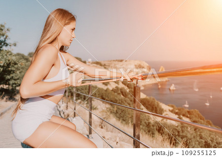 Fitness woman sea. Outdoor workout with fitness rubber bands in park over beach. Female fitness yoga routine concept. Healthy lifestyle. Happy fit woman exercising with rubber band in park. 109255125