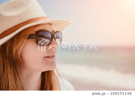 Young woman in red bikini on Beach. Blonde in sunglasses on pebble beach enjoying sun. Happy lady in one piece red swimsuit relaxing and sunbathing by turquoise sea ocean on hot summer day. Close up Young woman in red bikini on Beach. Blonde in sunglasses on pebble beach enjoying sun. Happy lady in one piece red swimsuit relaxing and sunbathing by turquoise sea ocean on hot summer day. Close up 109255148