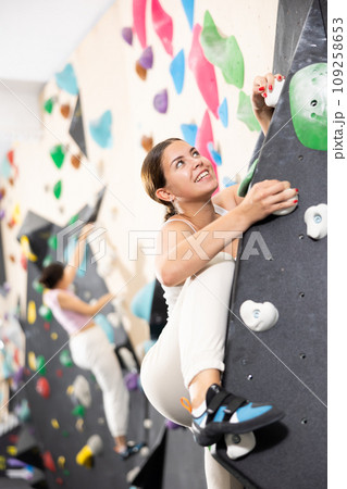Young female alpinist practicing indoor a rock-climbing on a artificial boulder without safety belts 109258653