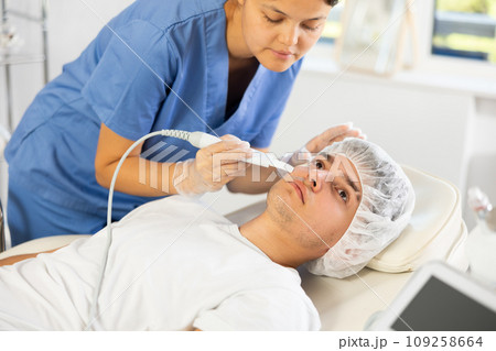Young woman cosmetologist doing exfoliation to young man 109258664