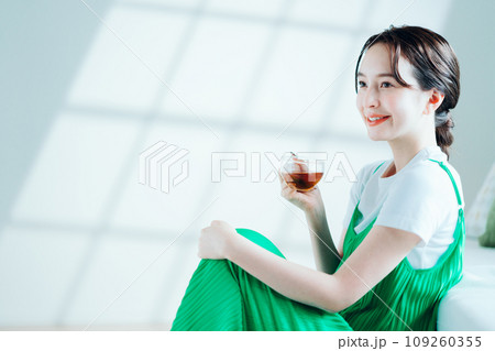 部屋でお茶を飲む若い女性。 109260355