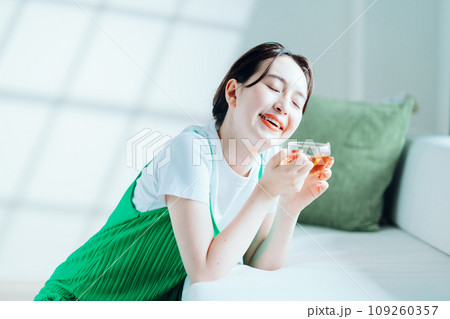 部屋でお茶を飲む若い女性。 109260357