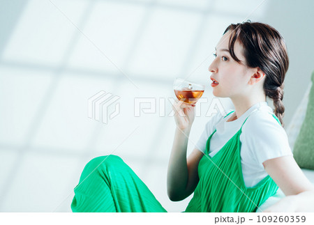 部屋でお茶を飲む若い女性。 109260359