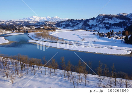 快晴の青空を背景に西日を浴びて白く輝く越後三山の雪山と信濃川の風景　Ver1 109262840