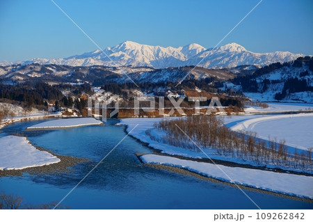 快晴の青空を背景に西日を浴びて白く輝く越後三山の雪山と信濃川の風景 Ver3 快晴の青空を背景に西日を浴びて白く輝く越後三山の雪山と信濃川の風景 Ver3 109262842