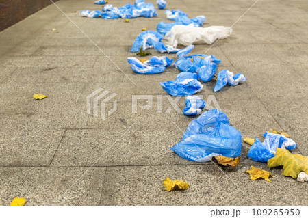Plastic shoe covers scattered in form of path. Ecology issues. Environmental pollution Plastic shoe covers scattered in form of path. Ecology issues. Environmental pollution 109265950