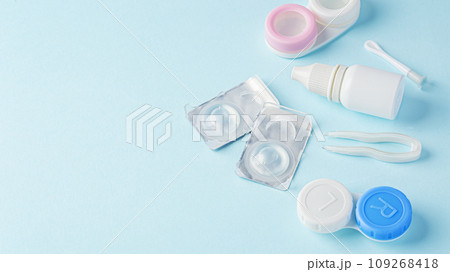 Contact lenses with container, eye drop and tweezer on blue background, copy space 109268418
