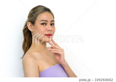 A closeup shot of young woman delicately touching her face, revealing details of her fingers, nails, and facial texture. Her eyes carry an expression of deep contemplation. 109268682