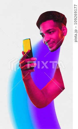 Poster. Contemporary art collage. One African American man with neon colored painted body holds smartphone against white studio background. 109269177