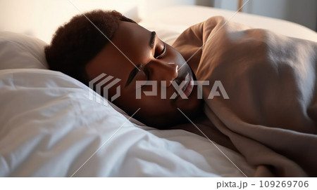 Young African-American man sleeps under warm plaid on soft bed at home closeup 109269706