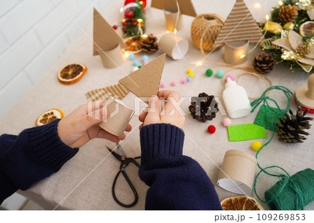 Step-by-step instructions on how to make a Christmas tree out of cardboard. Step 2 connect the upper triangular part with a cardboard roll stand. Zero waste concept. Step-by-step instructions on how to make a Christmas tree out of cardboard. Step 2 connect the upper triangular part with a cardboard roll stand. Zero waste concept. 109269853