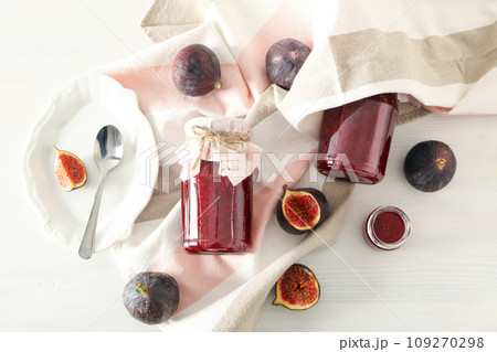 Figs, jars of jam and towel on light background, top view 109270298